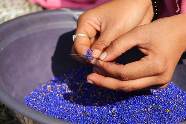 Hands working with blue small perls